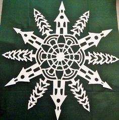 a snowflake made out of white paper on a green tablecloth with arrows