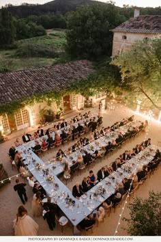 an aerial view of a formal dinner in the courtyard of a country house at dusk