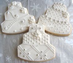 three decorated cookies sitting on top of a white cloth covered tablecloth with snowflakes