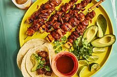 chicken skewers, avocado and salsa on a yellow plate with dipping sauce