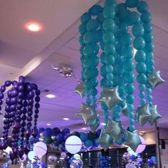 blue and purple balloons are hanging from the ceiling