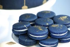 blue macaroons with white and gold sprinkles are on a plate