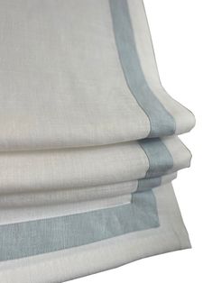 three pieces of white and grey linen with blue trims on each side, one folded up