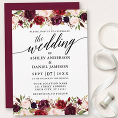 the burgundy and white floral wedding card is next to ribbon