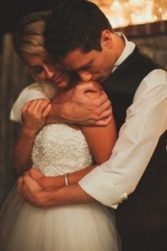 a bride and groom embracing each other in front of a fire at the end of their wedding day