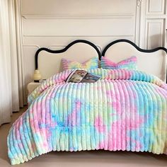 a bed with a colorful comforter and pillows on top of it in a room