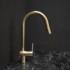 a gold faucet on a marble countertop in a black room with dark walls