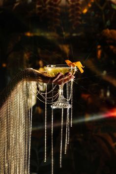 a person holding a glass with chains hanging from it