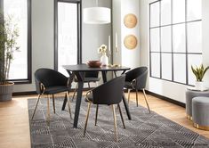 a dining room table with four chairs and a rug in front of the window, next to a potted plant