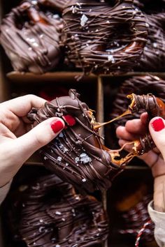 two hands picking up some chocolate covered donuts