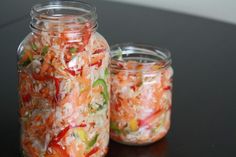 two mason jars filled with shredded vegetables on a table