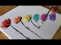 someone is painting colorful flowers on a canvas