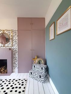 a pink and black room with polka dots on the walls, a white floor and a fireplace