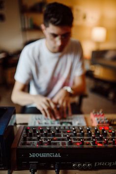 a man sitting in front of a sound mixing console with his hands on the knobs