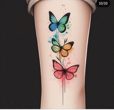 a woman's leg with colorful butterflies on it and watercolor paint splatters