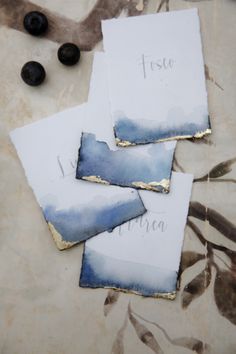 three pieces of paper sitting on top of a table next to some black olives