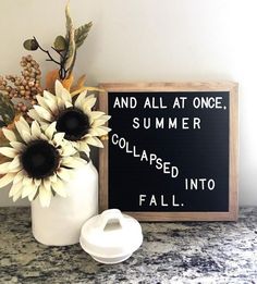 a vase with sunflowers in it next to a sign that says and all at once, summer collapsed into fall