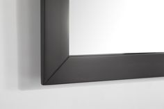 a mirror hanging on the wall above a sink in a room with white walls and black trim