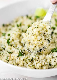 a white bowl filled with rice and garnished with parsley on the spoon