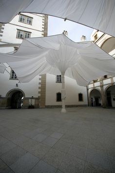 an open courtyard with white draping covering the ground and buildings in the background