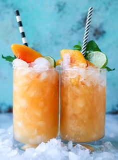 two glasses filled with drinks sitting on top of ice