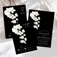 two black wedding cards with white flowers on them