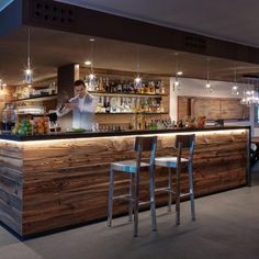 a bar with two stools in front of it and a man behind the bar