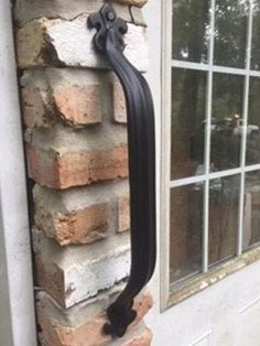 a window with a black handle attached to the side of a brick wall next to a white door