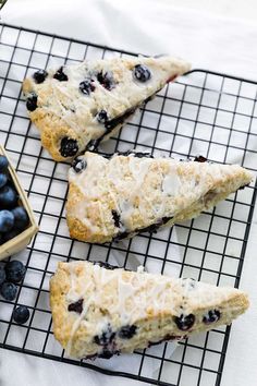 blueberry scones on a cooling rack next to a cup of tea and some berries