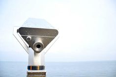 there is a camera on top of a metal pole near the ocean and water in the background