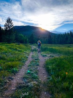 a person walking down a dirt road in the middle of a field