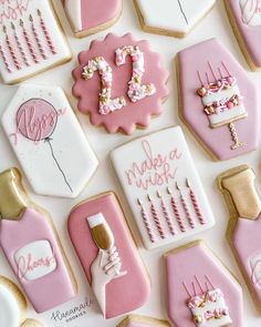 cookies decorated with pink and gold icing are arranged on a white tablecloth that says,