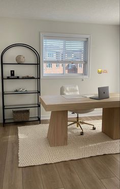 an office with a desk and shelves in the corner, along with a rug on the floor