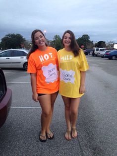 two girls in orange and yellow shirts standing next to each other near a parked car