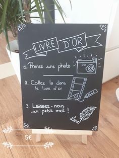 a blackboard sign sitting on top of a wooden floor next to a potted plant