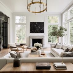 a living room filled with furniture and a fire place in front of two windows on either side of the fireplace