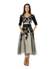 a woman wearing a dress with black and white flowers on the bodicet, in front of a white background