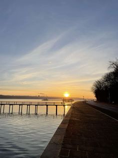 the sun is setting over the water and there are some docks in front of it