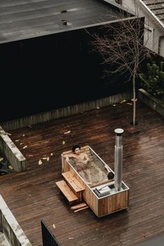 a hot tub sitting on top of a wooden deck next to a tree and building