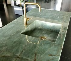 a green marble counter top with a sink and faucet in the middle,