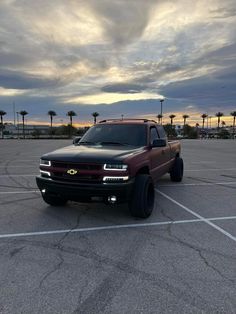 a truck is parked in a parking lot with palm trees and cloudy skies behind it