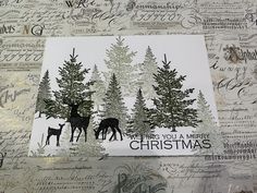 a christmas card with deer and trees in the background on a sheet of handmade paper