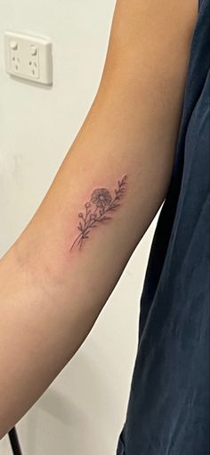 a woman's arm with a small flower tattoo on the left side of her arm