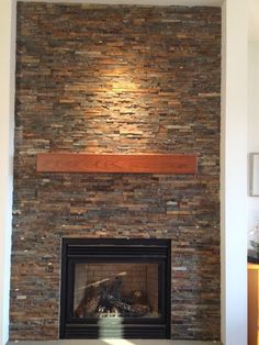 a fire place with a stone fireplace in the middle and a wooden mantle above it