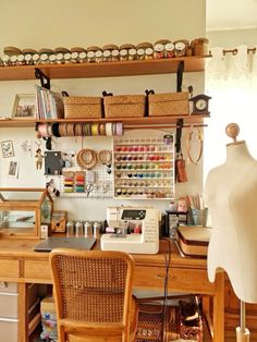 a sewing studio with lots of crafting supplies on the desk and shelves above it