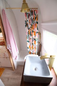 a bathroom with a sink, shower curtain and towel rack in front of the window