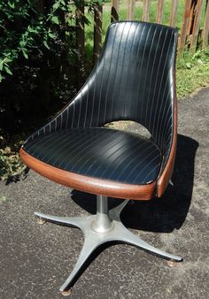 an office chair sitting on top of a metal base in front of a wooden fence