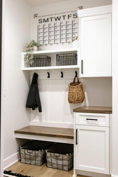 a mud room with white cabinets and baskets