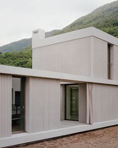 the house is made out of white corrugated and has sliding glass doors that open up to let in natural light