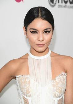 an image of a woman with dark hair wearing a white dress and posing for the camera